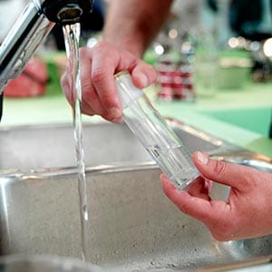 Close up photo of a man taking a water sample.