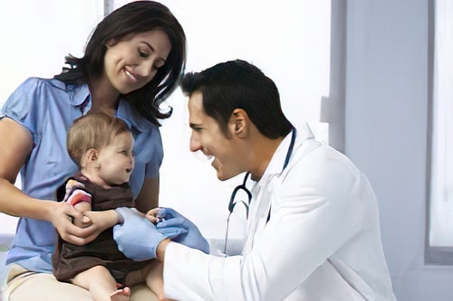 Healthcare provider evaluating a baby while mom is holding the child
