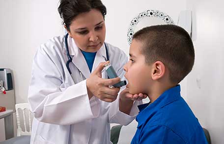 طبيب يعطي جهاز استنشاق للربو لصبي صغير.