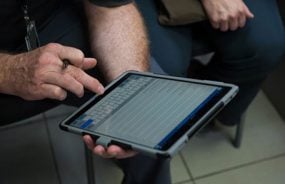 An image of a man entering data on a computer tablet