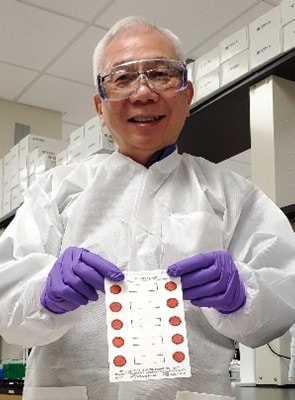El microbiólogo de investigación de los CDC, Francis Lee, sostiene gotas de sangre seca