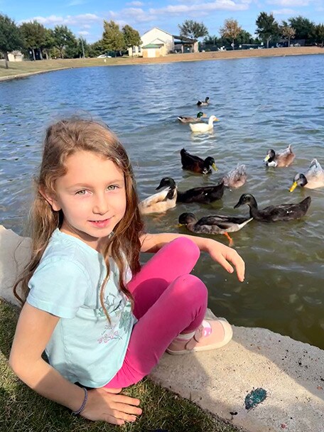 Villarreal family photo - Evelyn feeding ducks in a pond at the park.