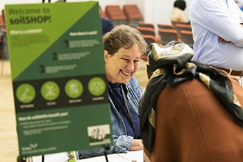 A person working an information table at a soilSHOP event.