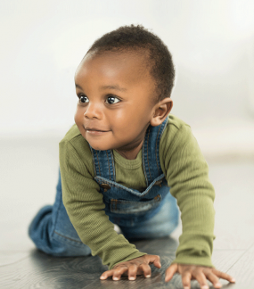 Image of an African American baby boy crawling on a floor.