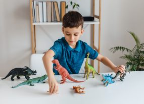 Boy playing with dinosaur toys on a table.