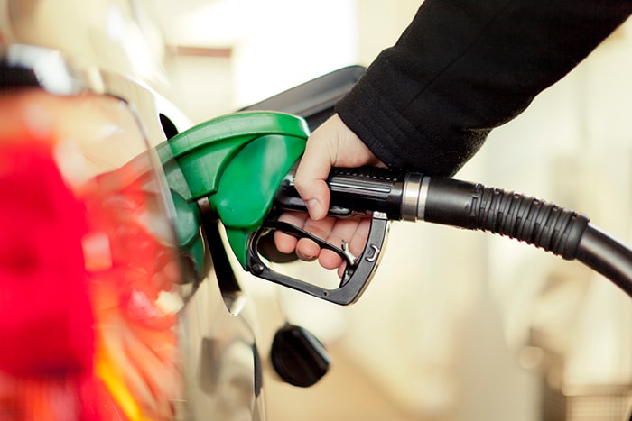 Image of an adult putting gas in a car. 