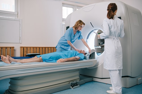 Radiologist with patient, health professional and CT scanner