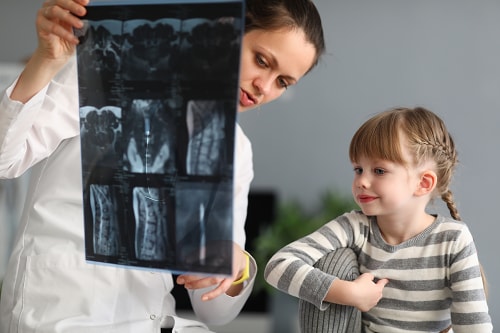 Pediatrician explaining x-ray with smiling young girl