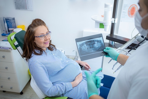 Pregnant woman in dentist office discussing dental x-ray