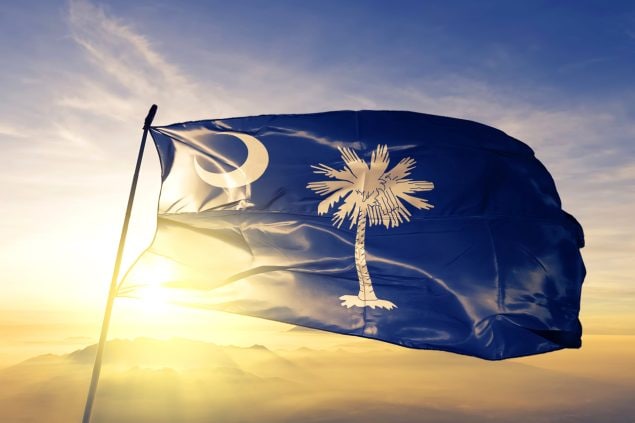South Carolina state flag waving in the wind with sunset behind