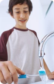 Boy brushing teeth using tap water