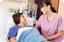 Middle-aged woman in hospital bed comforted by nurse