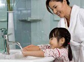Mother teaching daughter to wash hands
