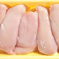 Pieces of raw chicken in a container.
