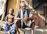 Older African Male with young boy sitting in village