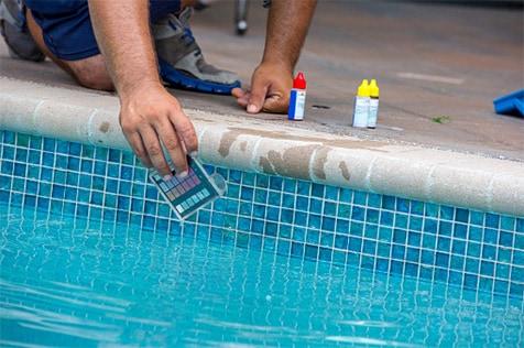Photo of a person testing pool water.