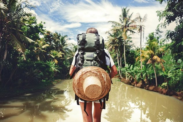 Backpacker standing in front of river in jungle
