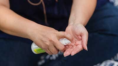 Photo of person spraying insect repellent into their hand.