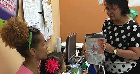 Healthcare worker providing patient education about Zika to a mother and her child.