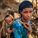 Young African mother carrying her baby on back, East Africa