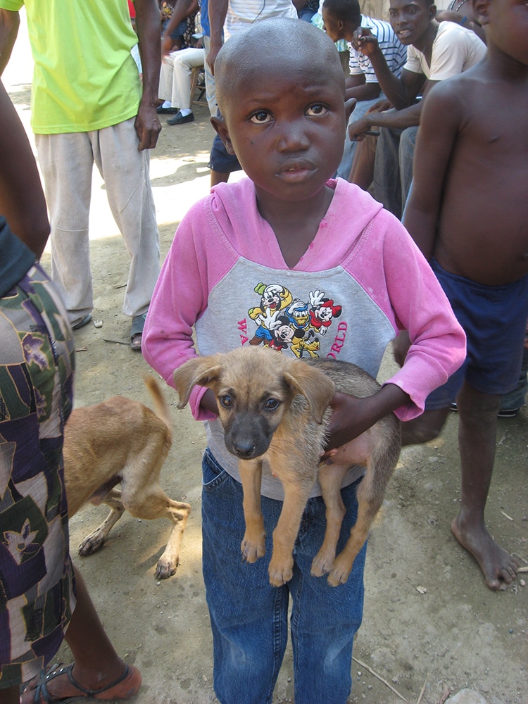 A little girl waits in line to get her puppy vaccinated against rabies at a clinic in Haiti