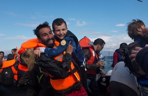 Image of man in life preserver holding a boy. Both with beautiful smiles.