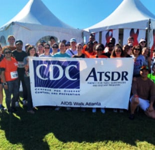A group of ATSDR and CDC colleagues near a banner for AIDS Walk Atlanta