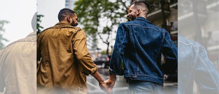 Two gay men holding hands while walking in an outdoor setting