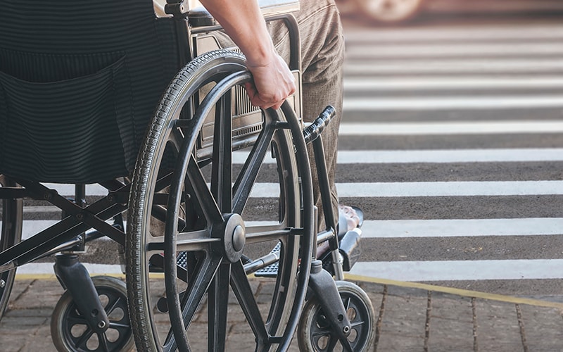 Disabled man on wheelchair crossing the road.