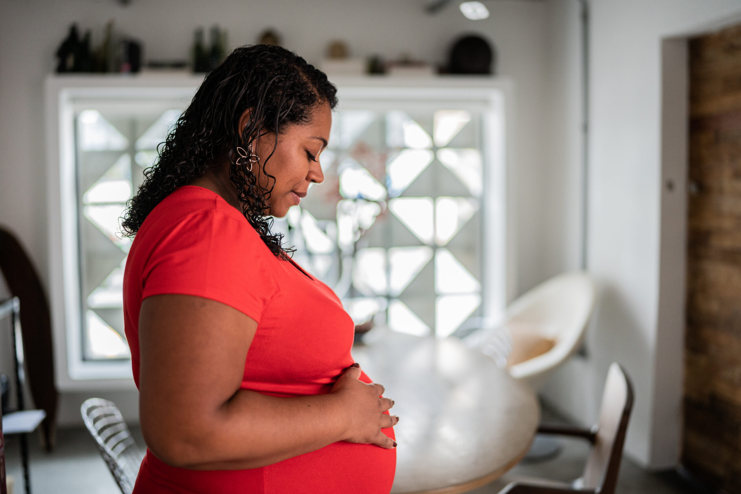 Pregnant woman contemplating with hands on belly