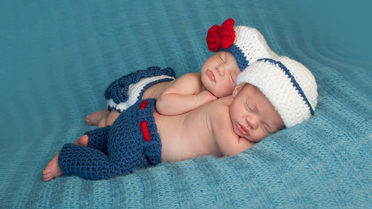 Twin babies dressed alike and lying together.