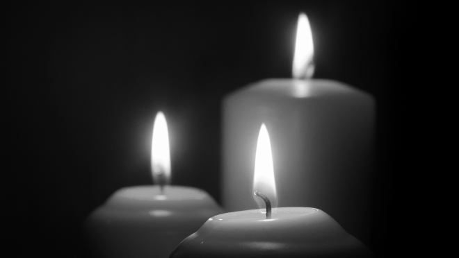 Three candles burning in a dark background.