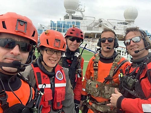 Group of workers in rescue gear smiling on a ship deck