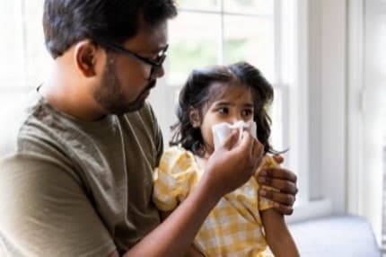 Father helps wipe daughter's nose