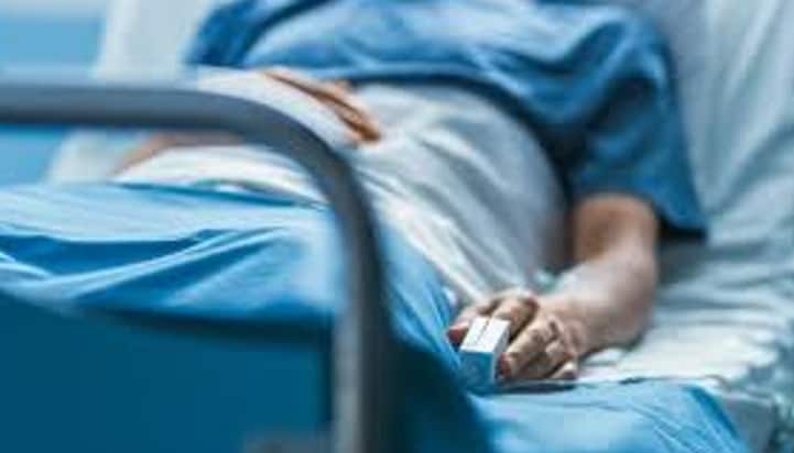 bottom half of a patient laying in a hospital bed wearing a blue gown