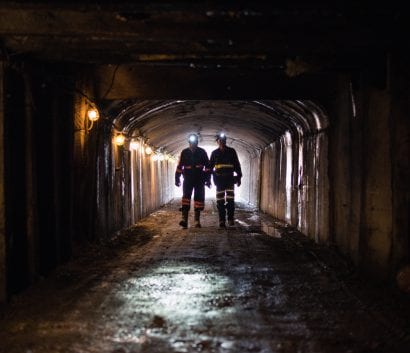 Two backlit miners in dark NIOSH Pittsburgh research mine entry 2018