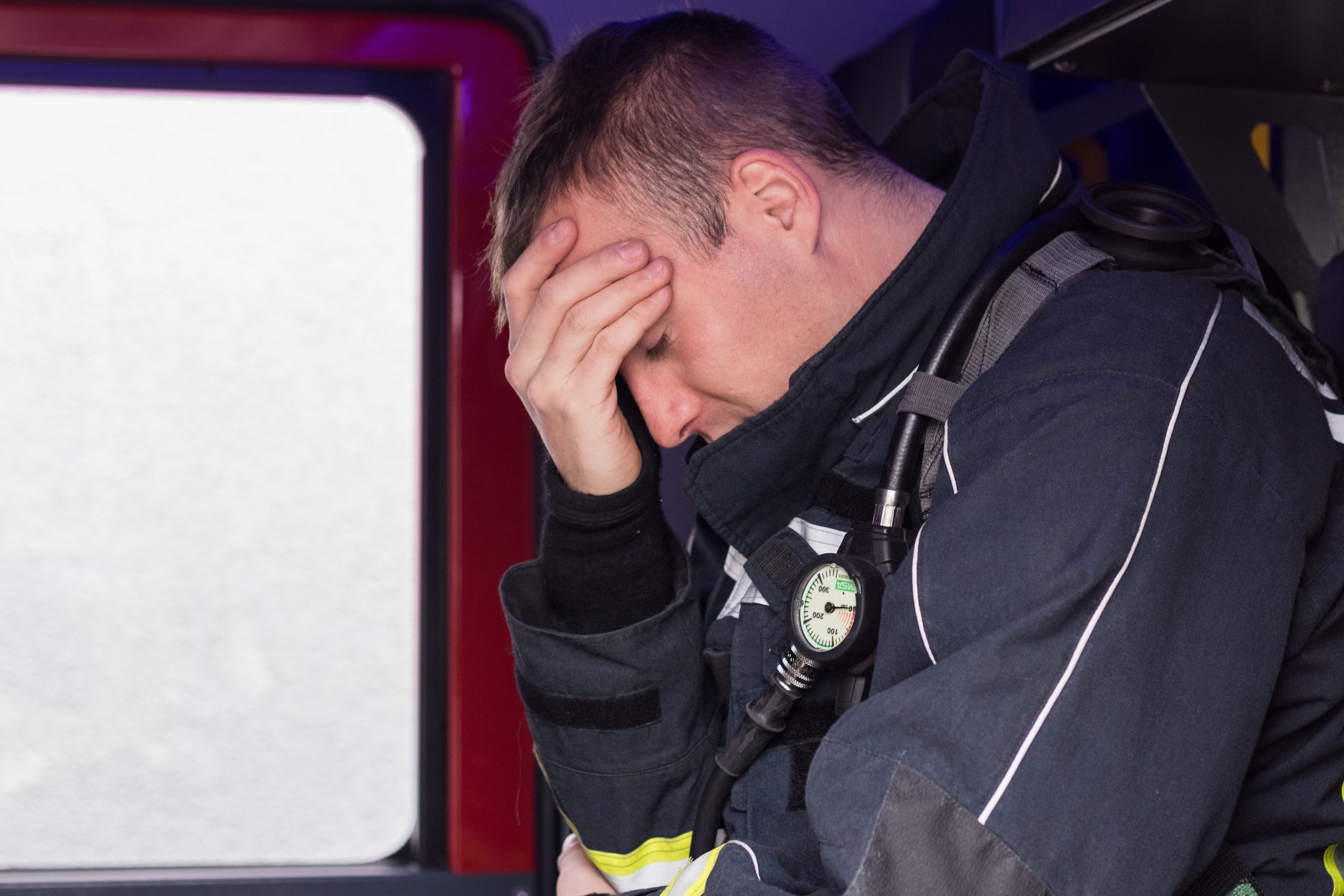 Fireman sitting on fire truck tired and sad