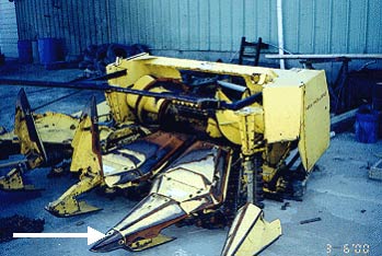 corn chopper head  disconnected from forage harvester, the arrow points to one of the tongs
