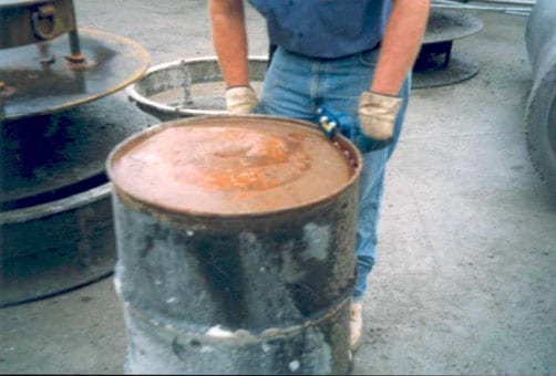 Employee using hand held drum opener to open a 55-gallon drum