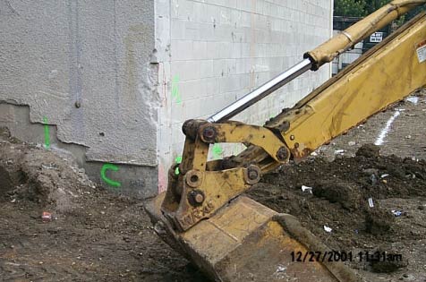 Exhibit #3. A view of the backhoe bucket and the wall with marking used for grading.