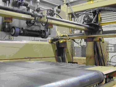 Exhibit #4. A picture of the rollers of the feed system that shuffles each box into the waxing system.