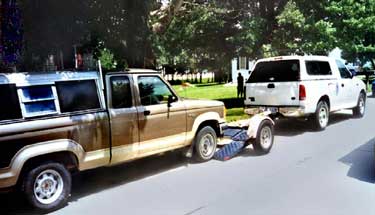 Photo 1 – Side view from the street showing both trucks and the 2-wheeled dolly.