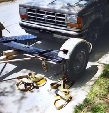 Photo 2– Closer view of the dolly showing hold-down straps on the ground and position of the vehicle-in-tow.