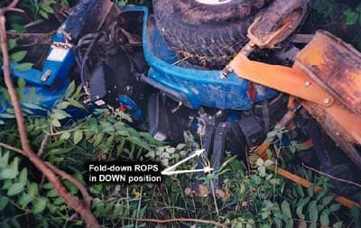 Photo 2 – Upside down tractor in the ditch, with foldable ROPS in the down position. Notice the mud around the hinge area from digging into the ground during overturn.