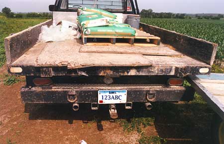 Photo 3 - View of rear of truck showing relative position of bumper and truck bed. Hay wagon shown to the right is typical, but is not the one involved in this incident.