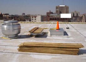 Figure 7. Make-up air roof curb with orange pylon, exhaust fan roof curb with plywood, looking north on roof. 