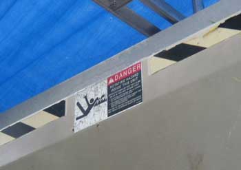 Safety label (in English) warning of the entanglement hazard inside the hopper.