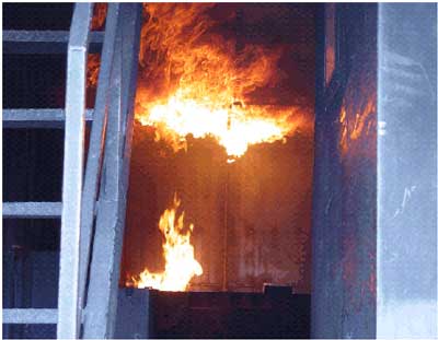 View thru rear doors showing cabinet prop at lower left and flashover bar at ceiling ignited; dividing partition walls have been swung out of way.