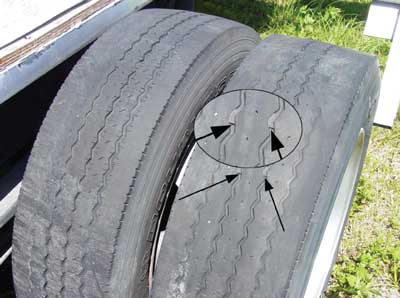 Photo 1. Illustrates the significant wear on one set of the rear tires. Arrows indicate the visible wear bars.