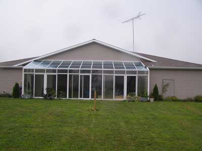 Rear side of the structure with a glass-enclosed porch covering an in-ground pool